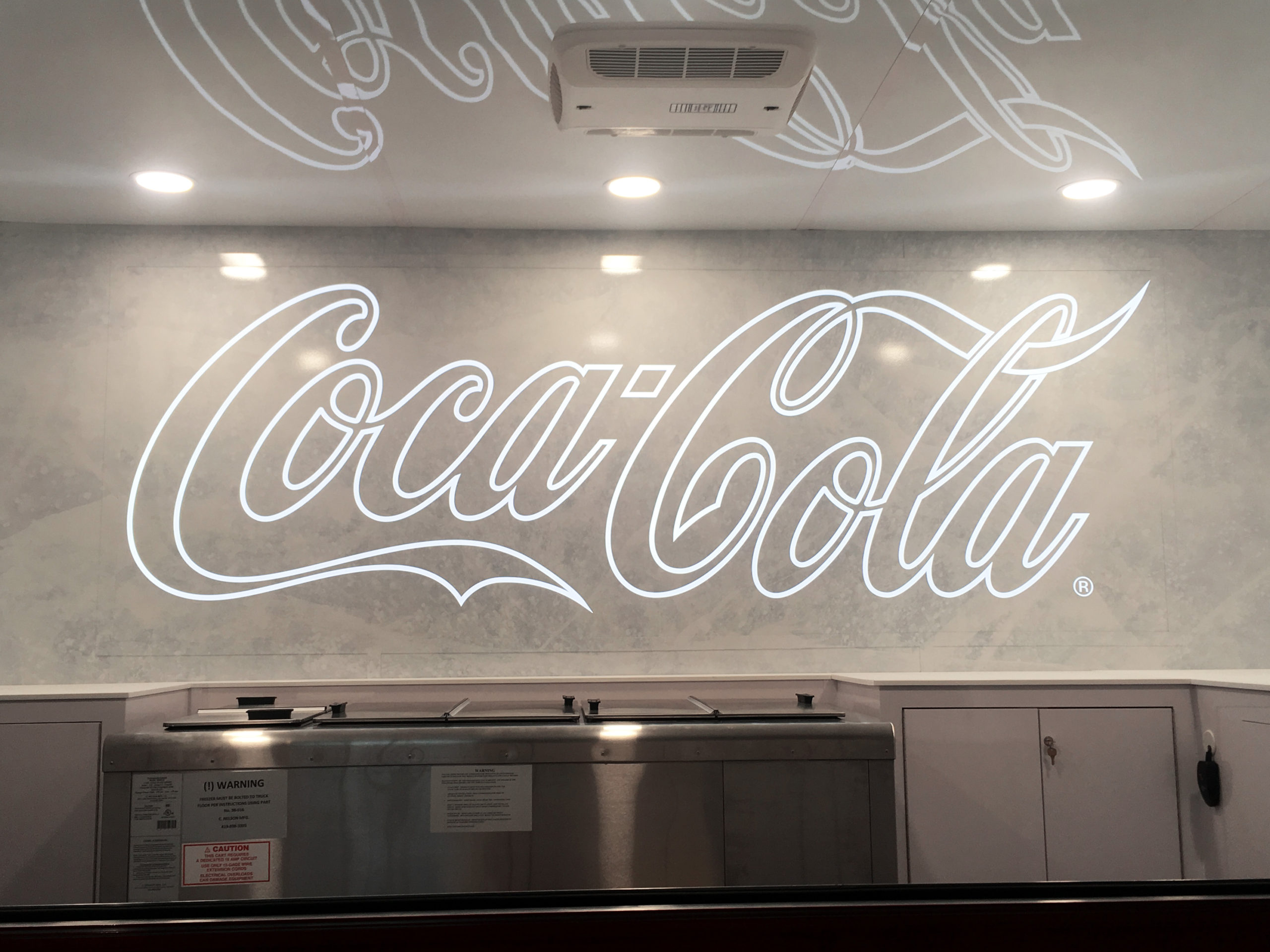 A white Coca Cola sign printed and installed by Turtle Transit.